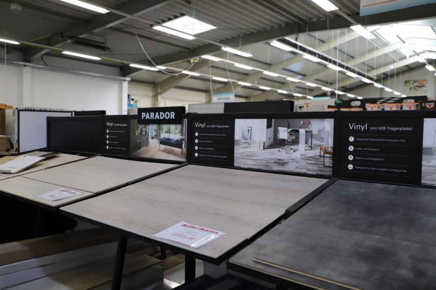 In einem Baumarkt werden verschiedene Vinylbodenbeläge auf großen Mustertafeln präsentiert.